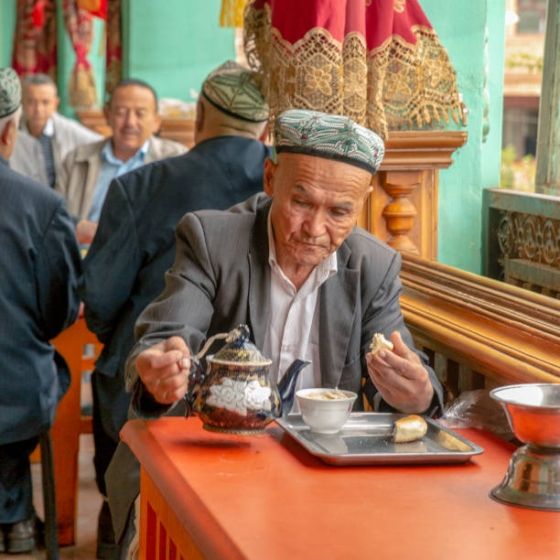 Kashgar, Xinjiang, China - September 5, 2018: Old man drinking tea in a traditional old tea house in Kashgar
